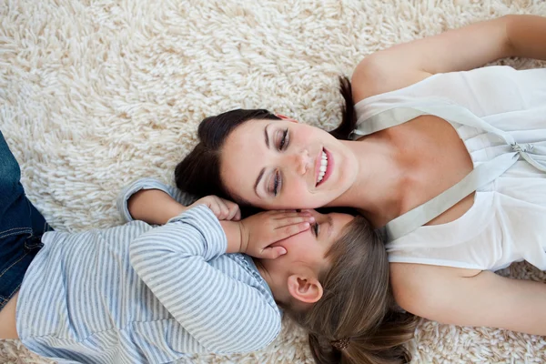 Sorridente madre e sua figlia sdraiata sul pavimento — Foto Stock