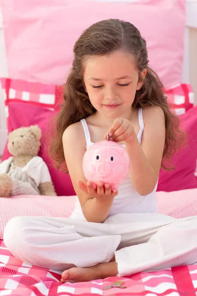Leende flicka att spara pengar i en piggybank — Stockfoto