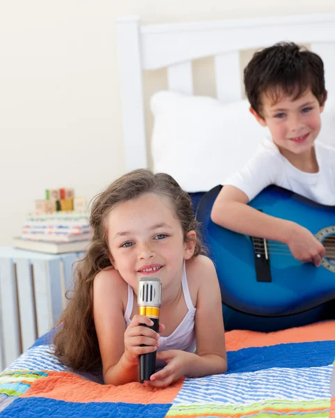 Close-up of a cute girl girl singing and her brother playing gui — Stock Photo, Image