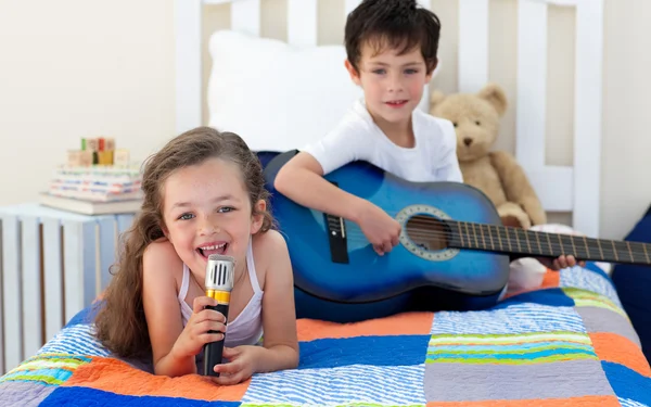 Mały chłopiec gra gitara i jego siostra, śpiew — Zdjęcie stockowe