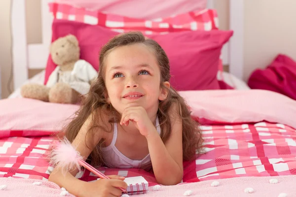 stock image Smiling girl writing on bed
