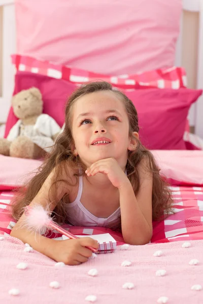 Portret van een klein meisje liggend op bed — Stockfoto