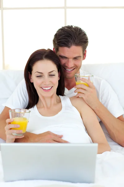 Lovers using a laptop on their bed — Stock Photo, Image