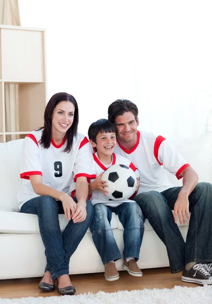 Веселая молодая семья смотрит футбольный матч — стоковое фото