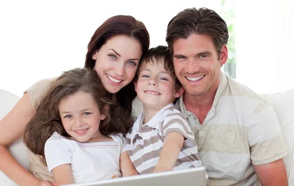 Família sorridente usando um laptop — Fotografia de Stock