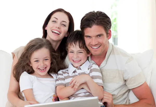 Усміхнена сім'я використовує ноутбук у вітальні — стокове фото