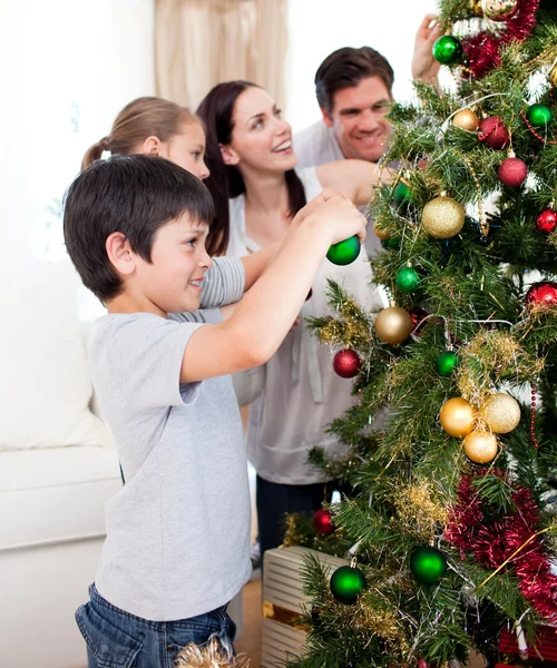 Ευτυχισμένη οικογένεια στολίζει ένα χριστουγεννιάτικο δέντρο με boubles — Φωτογραφία Αρχείου