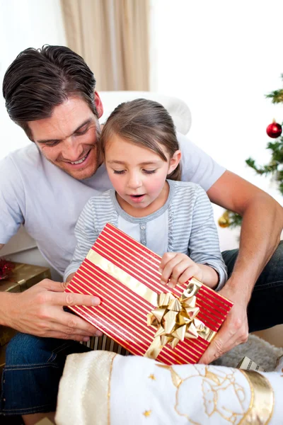 Förvånad liten flicka som håller en julklapp med hennes Henrik — Stockfoto