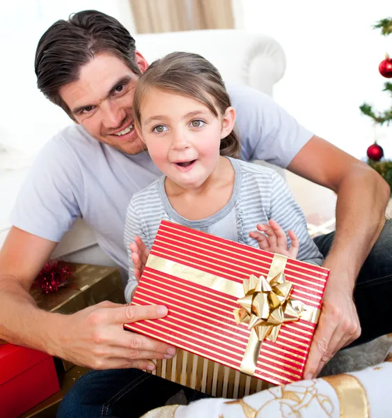 Happy little girl with her father receiving a Christmas present — Stock Photo, Image
