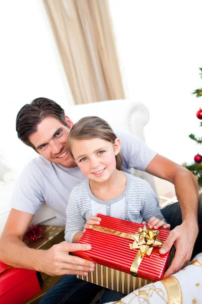 S úsměvem holčička se svým otcem drží vánoční dárek — Stock fotografie