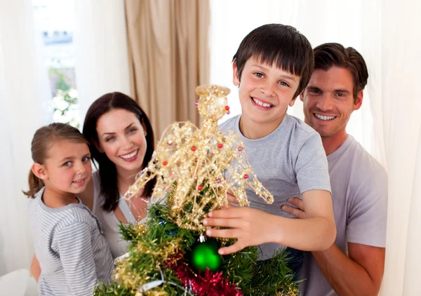 Menino feliz decorando uma árvore de Natal com sua família — Fotografia de Stock
