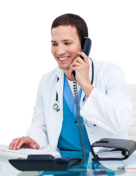 Bir bilgisayarda çalışan telefon üzerinde genç erkek doktor — Stok fotoğraf