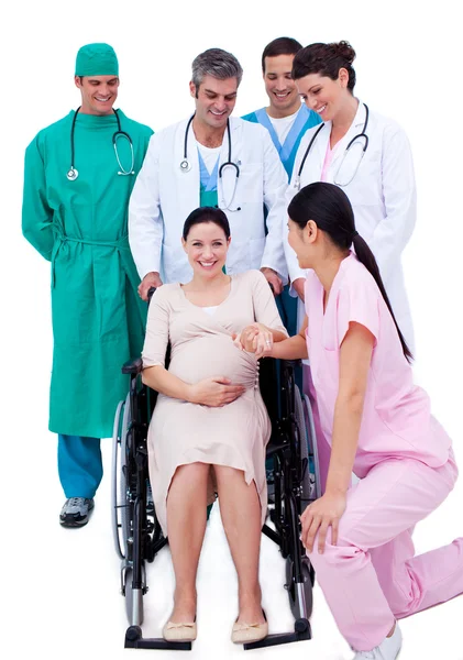 Красивая беременная женщина, сидящая в инвалидном кресле и медицинская команда — стоковое фото