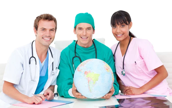 Vrolijke medisch team op zoek in terrestrische globe — Stockfoto