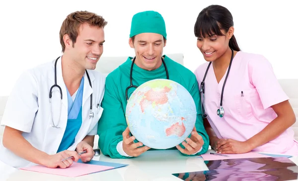 Веселая команда медиков смотрит на земной шар — стоковое фото