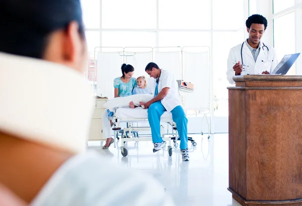 Injured woman sitting on wheelchair and a medical team at work — Stock Photo, Image