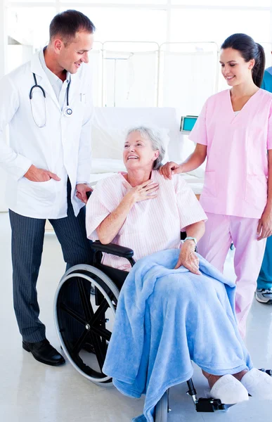 Lächelndes Ärzteteam kümmert sich um eine Seniorin — Stockfoto