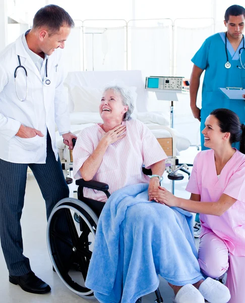Equipe médica confiante cuidando de uma mulher idosa — Fotografia de Stock