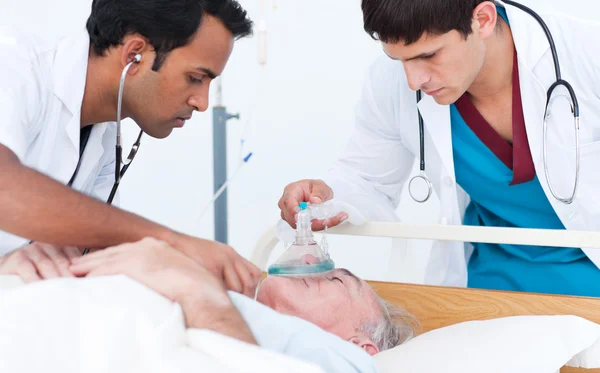 Giovane medico mettere maschera di ossigeno su un paziente anziano — Foto Stock