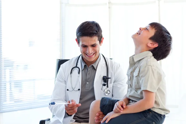 Smiling doctor checking a child's reflex — Stock Photo, Image