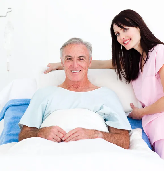 Enfermera sonriente arreglando la cama de un paciente mayor —  Fotos de Stock