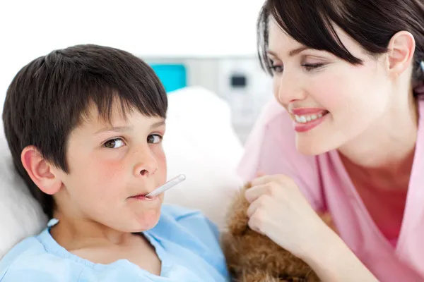 Очаровательная медсестра измеряет температуру маленького мальчика — стоковое фото