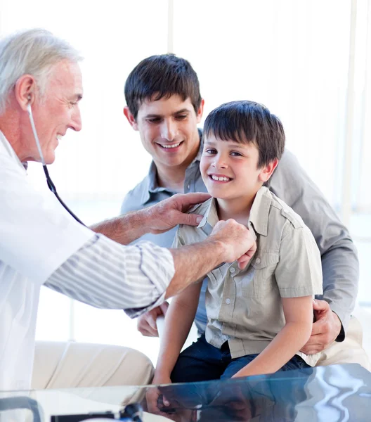 Positive doctor examining a little boy with his father — Stock Photo, Image