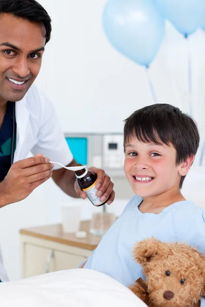 Усміхнений лікар вивчає маленького хлопчика з батьком — стокове фото