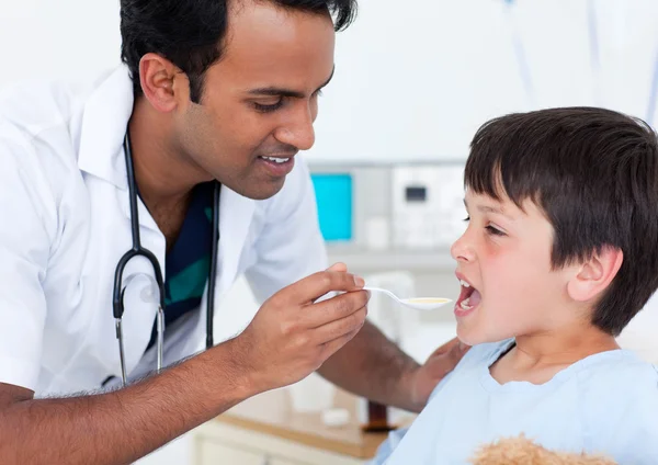 Aantrekkelijke dokter geneeskunde te geven aan een kleine jongen — Stockfoto