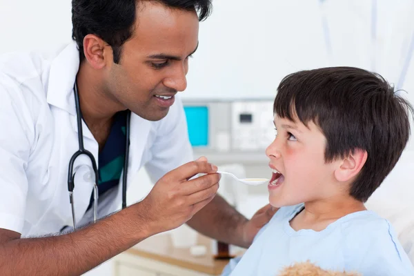 Jovem médico dando remédio para um menino — Fotografia de Stock