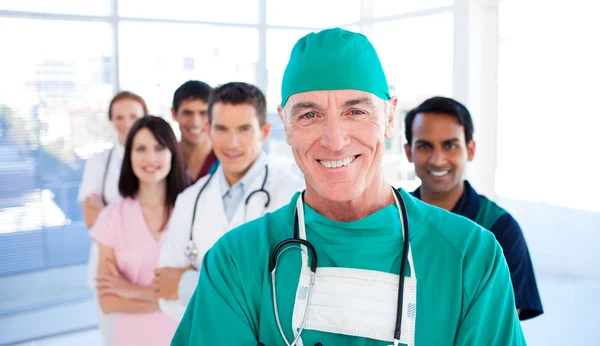 自信的资深外科医生，站在与他的同事们 — 图库照片