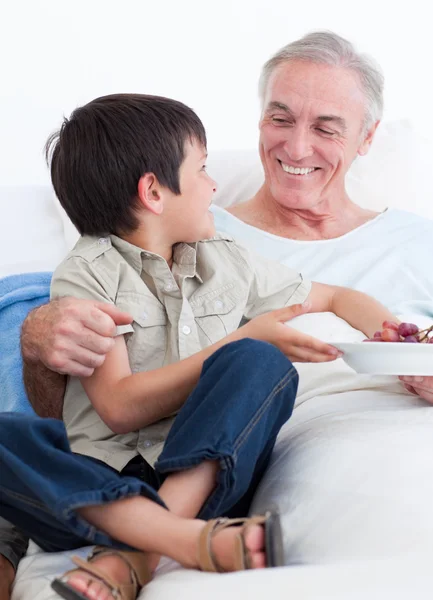 Adorable little boy taking care of his grandfather — Stock Photo, Image