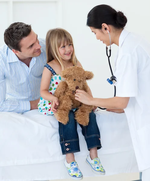 Un médecin examine un enfant souriant et joue avec un ours en peluche — Photo