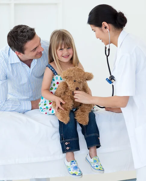 Kadın doktor ve mutlu küçük kız incelenirken bir oyuncak ayı — Stok fotoğraf