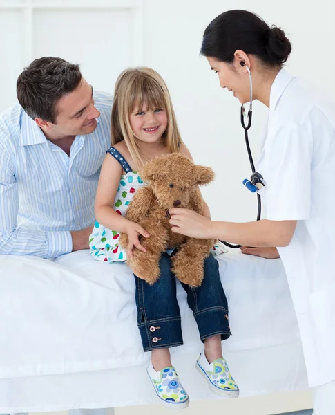 Femme médecin et heureuse petite fille examinant un ours en peluche — Photo