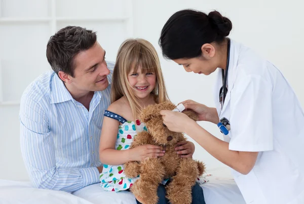 Sonriente paciente examinando un osito de peluche con un doctor — Foto de Stock