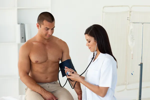 Pewnie lekarz kobiece kontroli ciśnienia krwi pacjenta — Zdjęcie stockowe