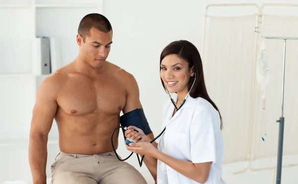 Médico sonriente revisando la presión arterial de un paciente — Foto de Stock