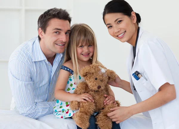 Porträtt av en läkare och glad liten tjej undersökt en nallebjörn — Stockfoto