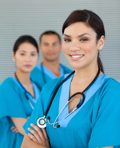 Aantrekkelijke vrouwelijke arts met zijn collega's op de achtergrond — Stockfoto