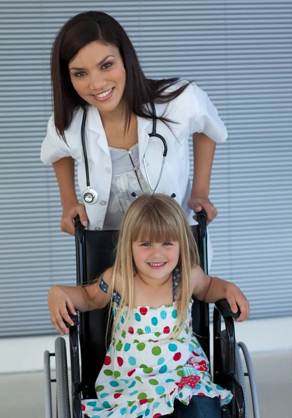 Portrait of a little girl on a wheelchair and a young doctor — Stock Photo, Image