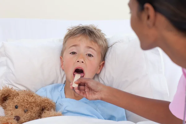 Медсестра проверяет горло мальчика в больнице — стоковое фото