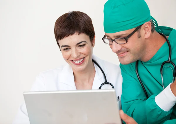 Médico y cirujano mirando un portátil — Foto de Stock