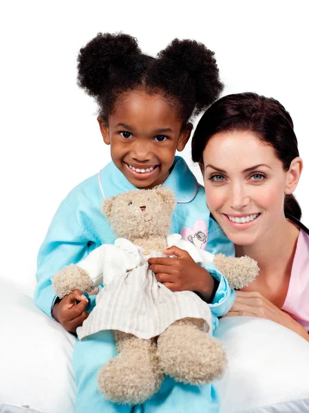 Улыбающаяся маленькая девочка с медсестрой, смотрящей в камеру — стоковое фото