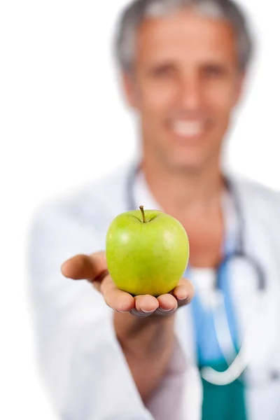 Médico sorridente apresentando uma maçã verde — Fotografia de Stock