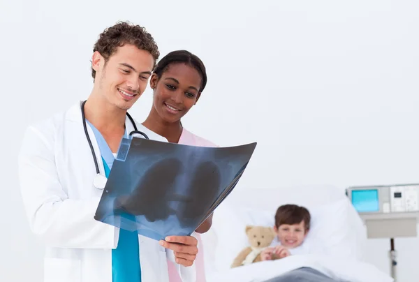 Doutor e enfermeira examinando um raio-x no filho de um quarto — Fotografia de Stock