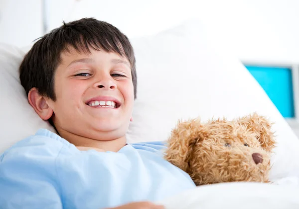 Niño sonriente acostado en una cama de hospital —  Fotos de Stock