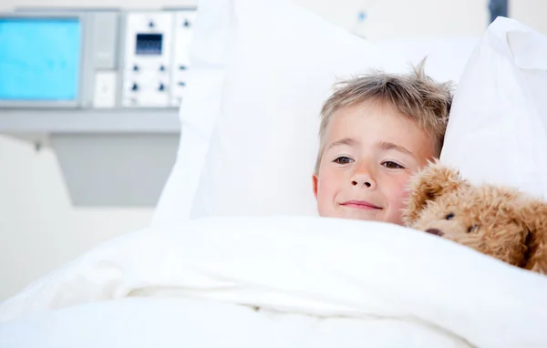 Ziek schattige kleine jongen in een ziekenhuisbed liggen — Stockfoto