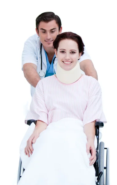 Привлекательный врач-мужчина несет пациента в инвалидном кресле — стоковое фото
