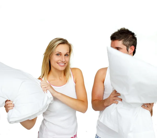 Beautiful woman having a pillow fight with a man — Stock Photo, Image